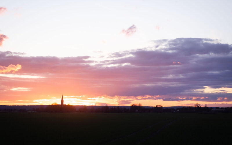 prächtiger Sonnenuntergang vor einer Kirche am Horizont